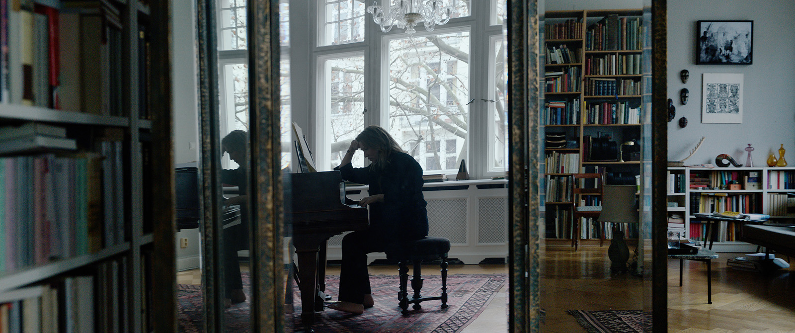 Lydia accoudée à son piano, face à un miroir